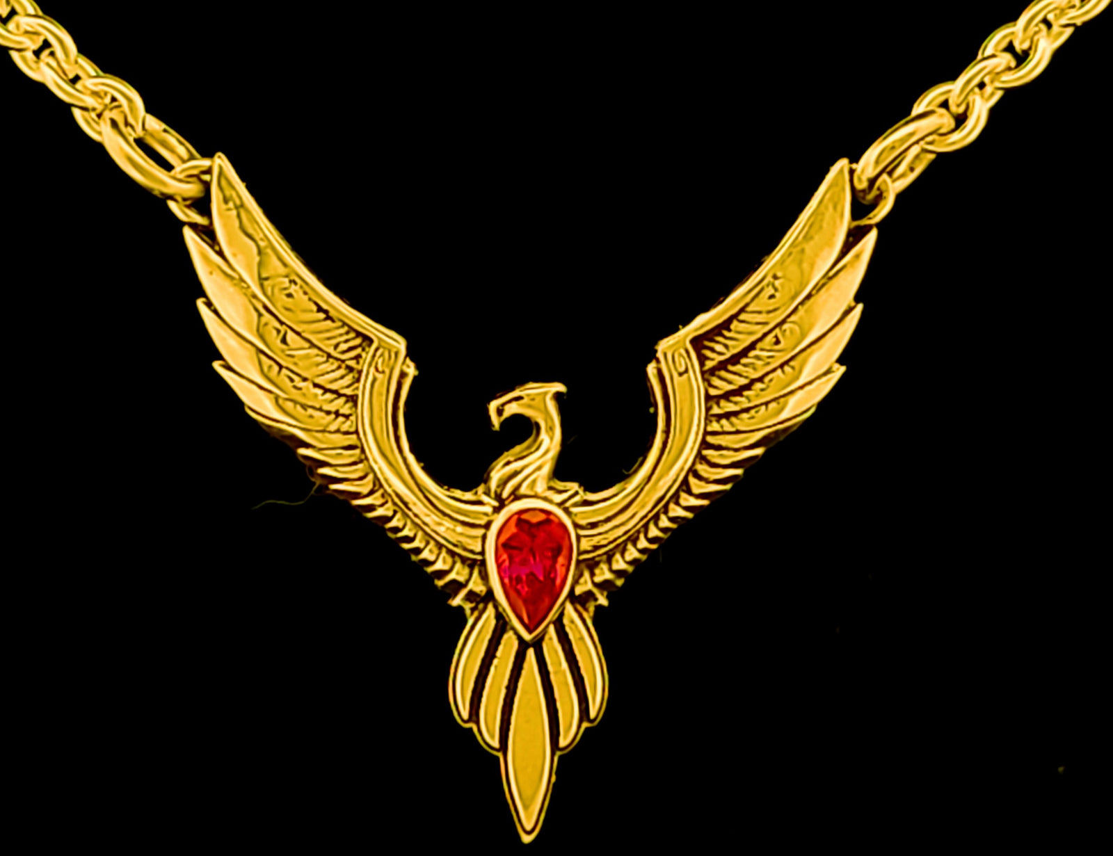 a gold necklace with a red stone in the center