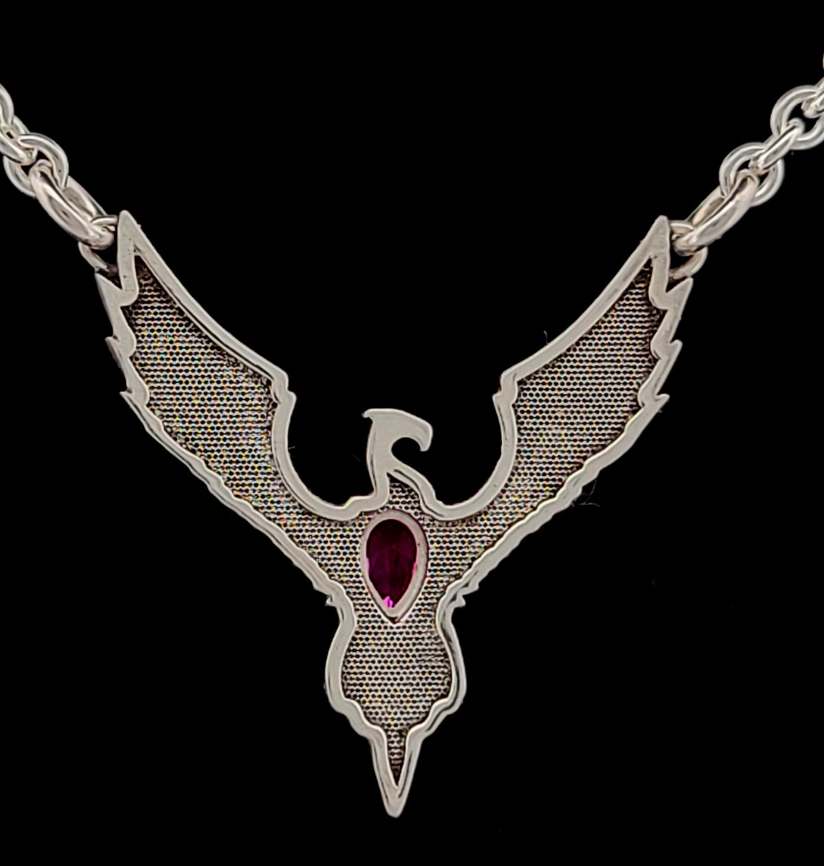 a silver necklace with a red stone on it